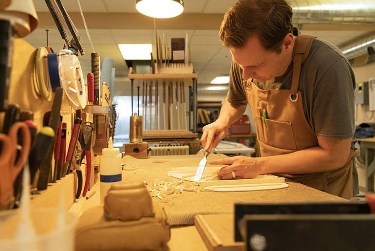 Yamaha Guitar Development Senior Acoustic Guitar Builder Andrew Enns carving top braces on workbench