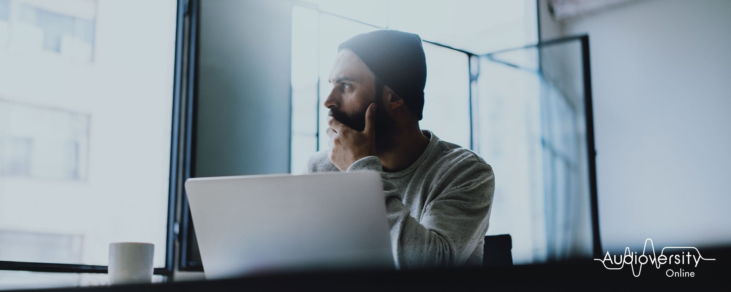 Key visual for Audioversity Online: a man wearing a hat with a serious expression.