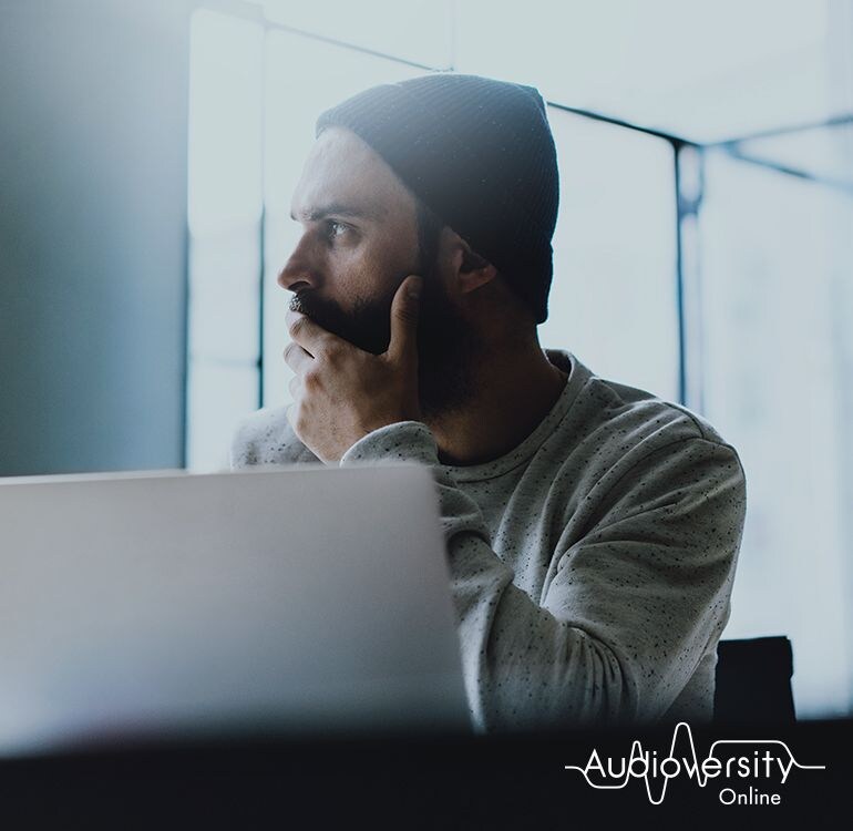 Key visual for Audioversity Online: a man wearing a hat with a serious expression.