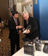 Alan Frew signs a copy of his book The Action Sandwich for President Kenichi Matsushiro