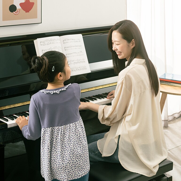 Une mère et sa fille ont du plaisir à jouer du piano droit de la série B