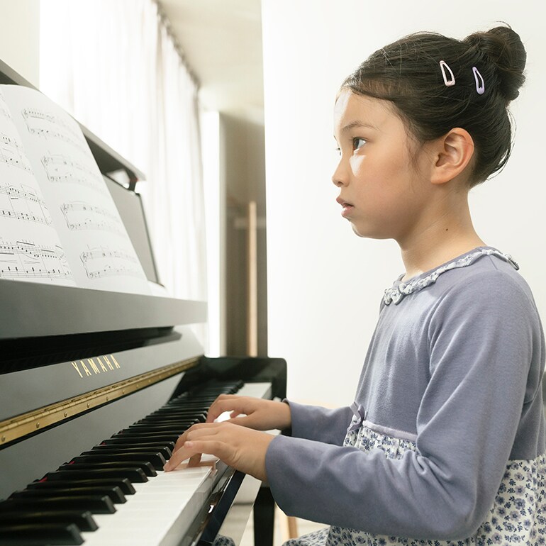 Un enfant joue avec plaisir du piano droit de la série B