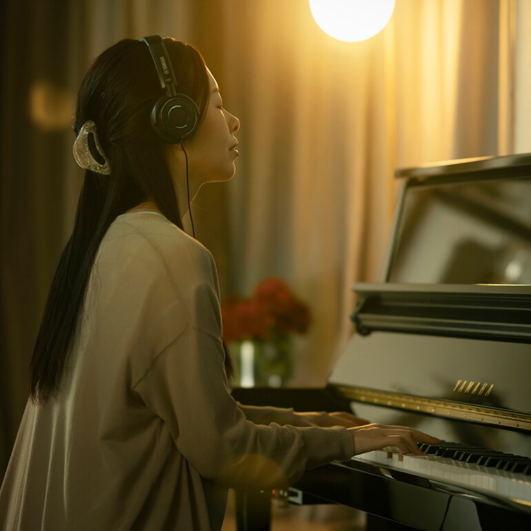 Une femme joue avec plaisir du piano tout en portant un casque d'écoute