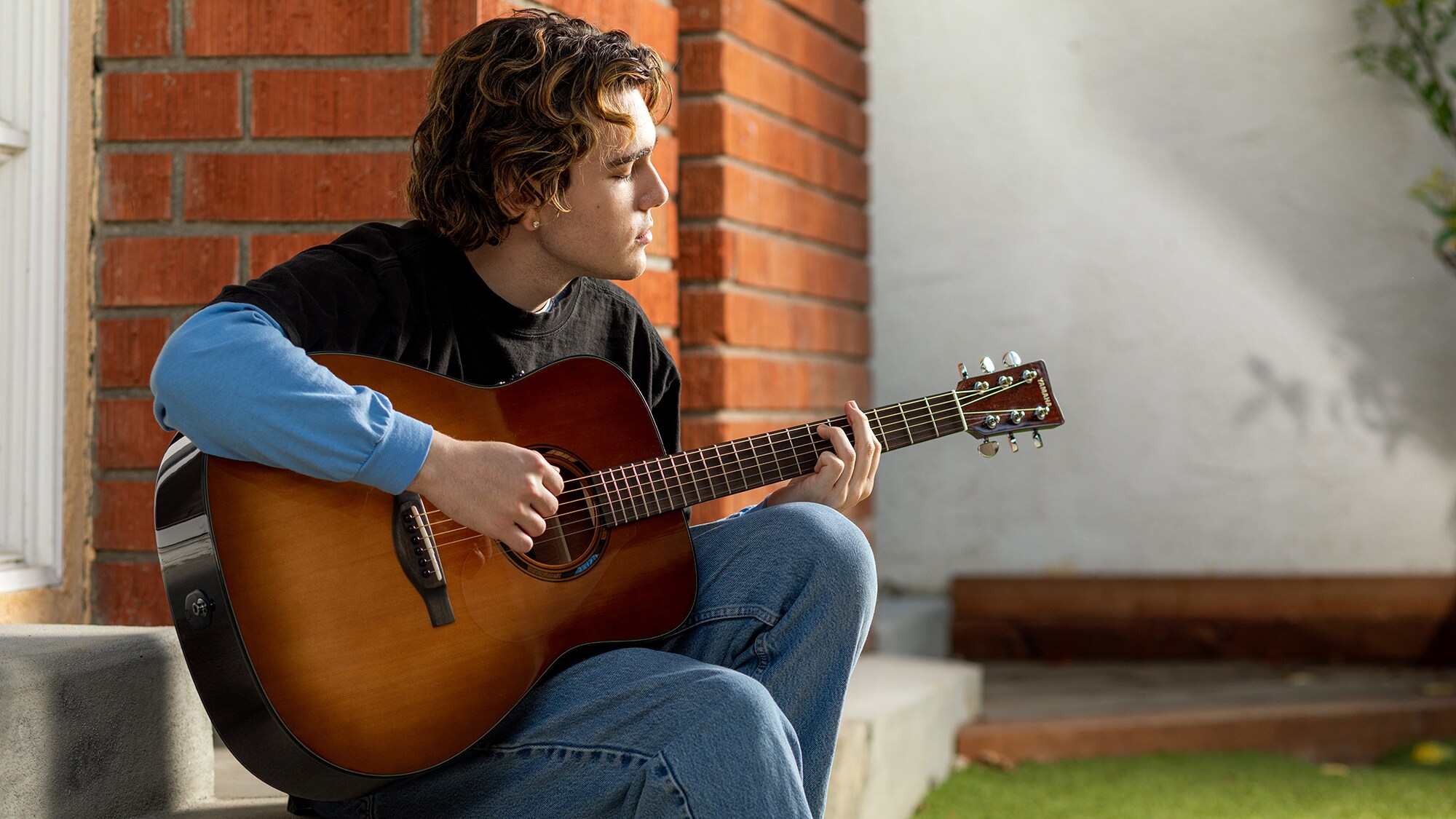 Un homme jouant d'une guitare acoustique TAG1E à l'extérieur