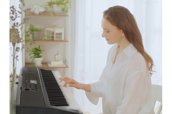Woman playing the PSR-EW320 with one hand.