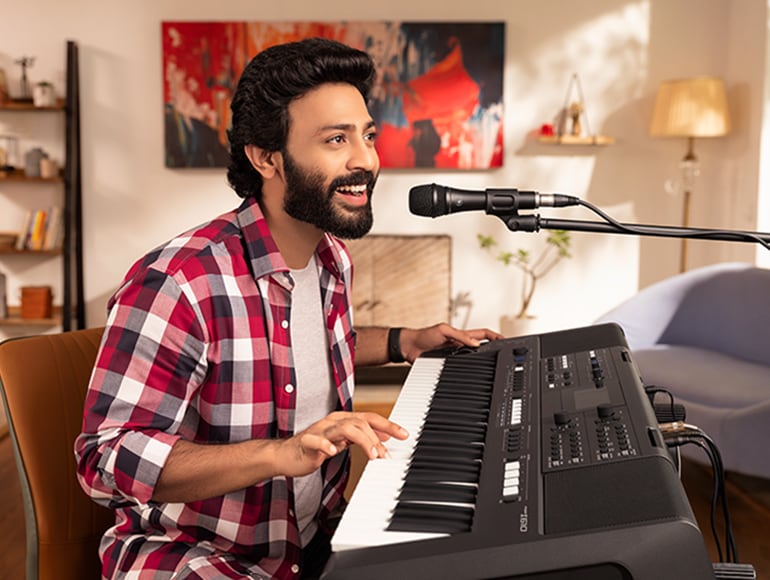 Un amateur joue et chante avec un micro connecté au PSR-I610.