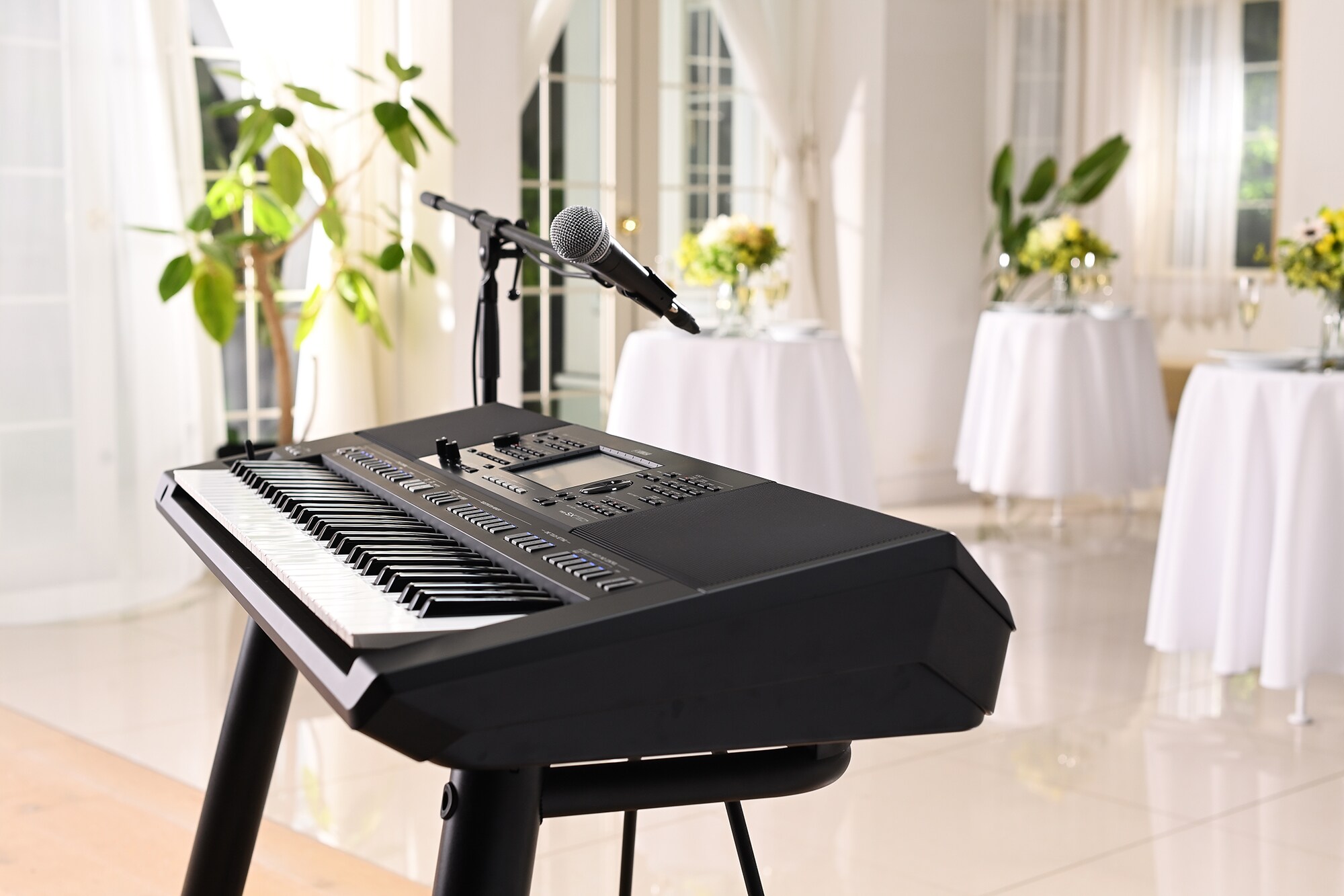 Station de travail arrangeur Yamaha PSR-SX720+ avec support de microphone dans une salle de réception.