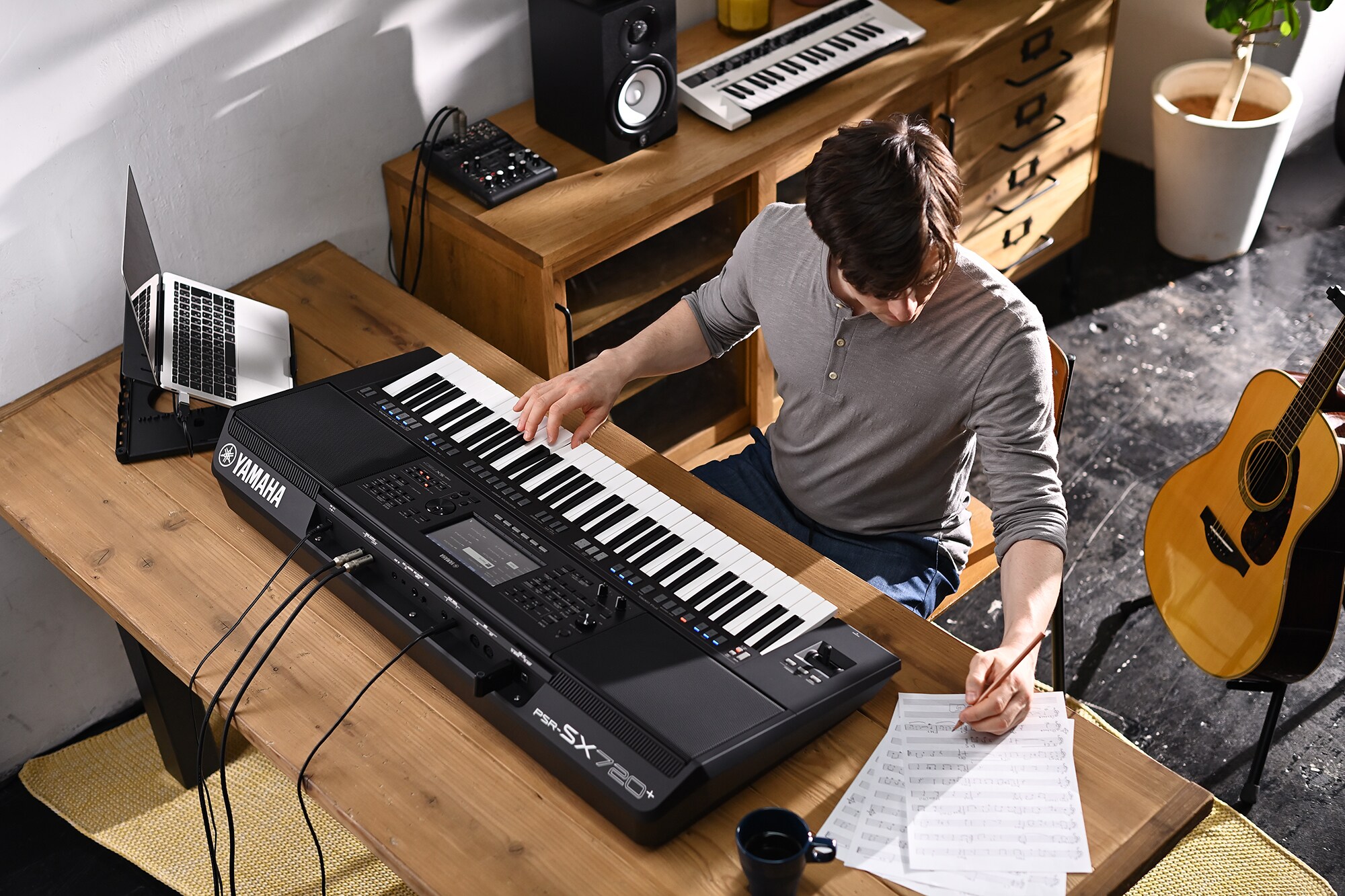 Photo d'une personne écrivant sur une partition tout en jouant sur la station de travail arrangeur Yamaha PSR-SX720+
