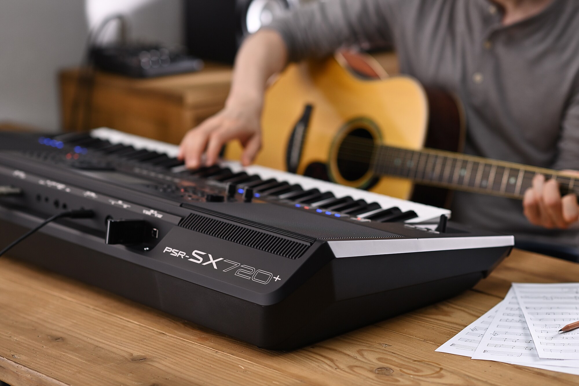 Photo d'une personne jouant sur la station de travail arrangeur Yamaha PSR-SX720+ tout en tenant une guitare