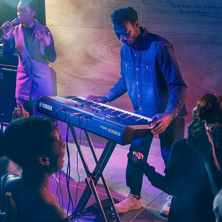 Une personne jouant sur le clavier portable Yamaha PSR-E583 sur scène