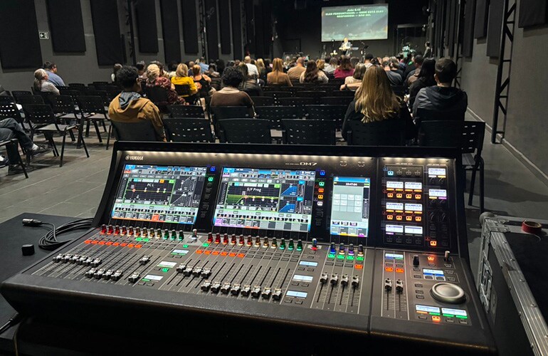 Centre de formation de São Paulo avec des consoles de mixage numériques et des participants dans une salle de formation audio professionnelle.