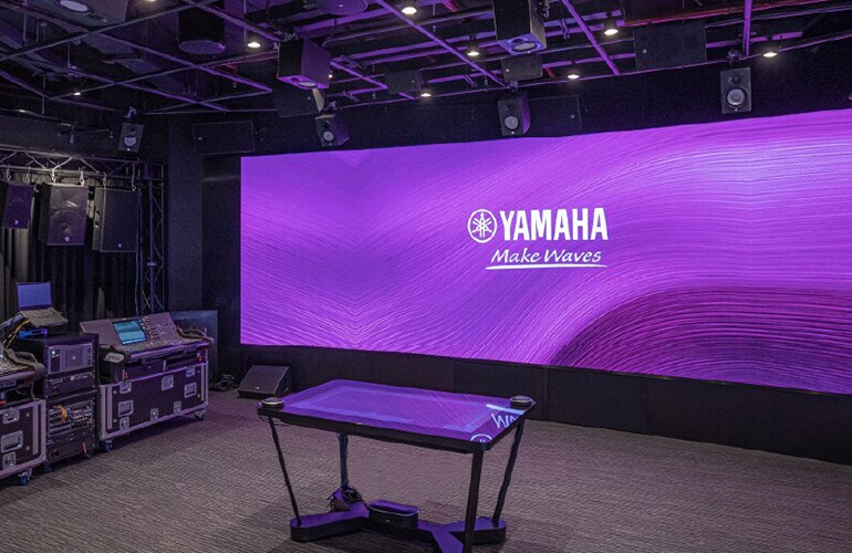 Centre de formation de Bangkok avec mur d'affichage Yamaha, espace scène et équipement audio professionnel.