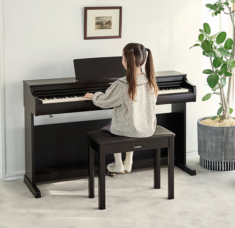 Une jeune fille s'exerçant sur un piano ARIUS dans un salon