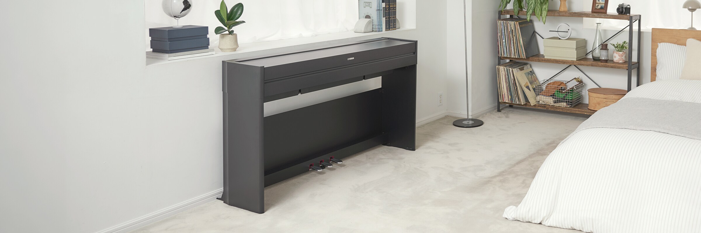 Un piano ARIUS dans une chambre à coucher avec son couvercle fermé, s'intégrant harmonieusement au décor