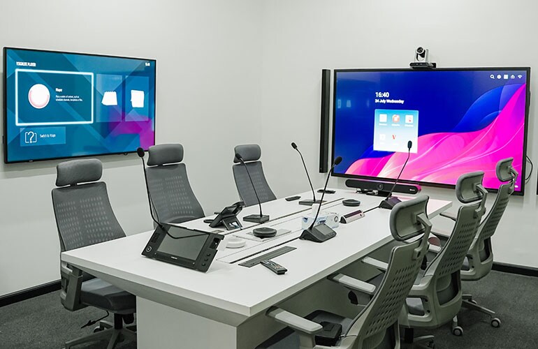 Salle de réunion du centre de formation de Dubaï avec table de conférence, écrans vidéo et équipement de présentation.