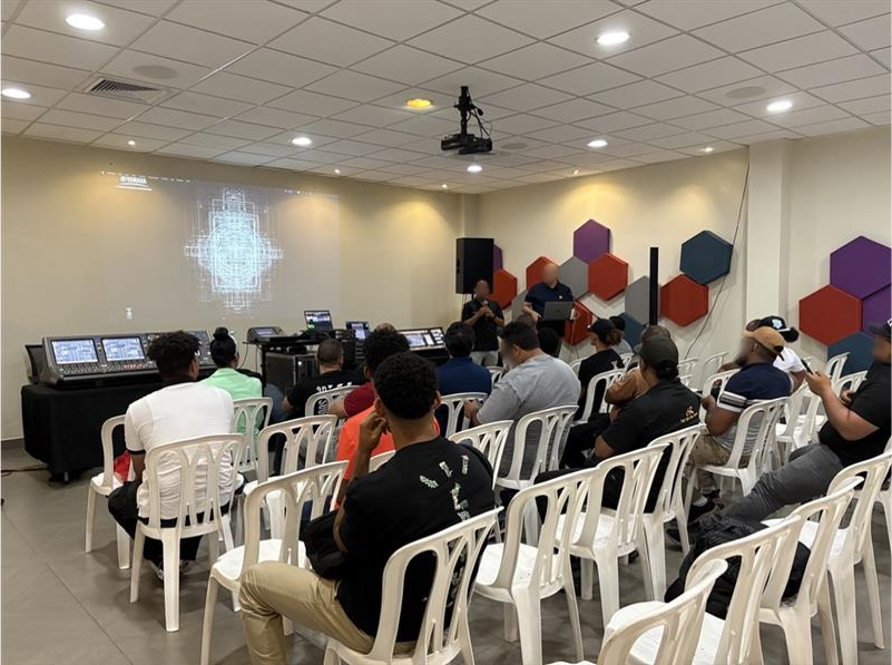 Centre de formation de Saint-Domingue avec des participants assis lors d'une séance de formation audio en configuration salle de classe.