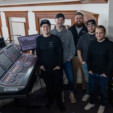 Des membres de l'équipe audio de Christ Community Chapel debout à côté d'une console de mixage Yamaha RIVAGE PM.